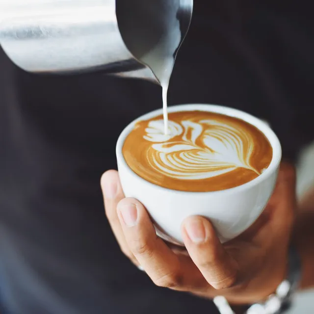 Taza de café con leche recién servida, con espuma cremosa, sobre una mesa de madera